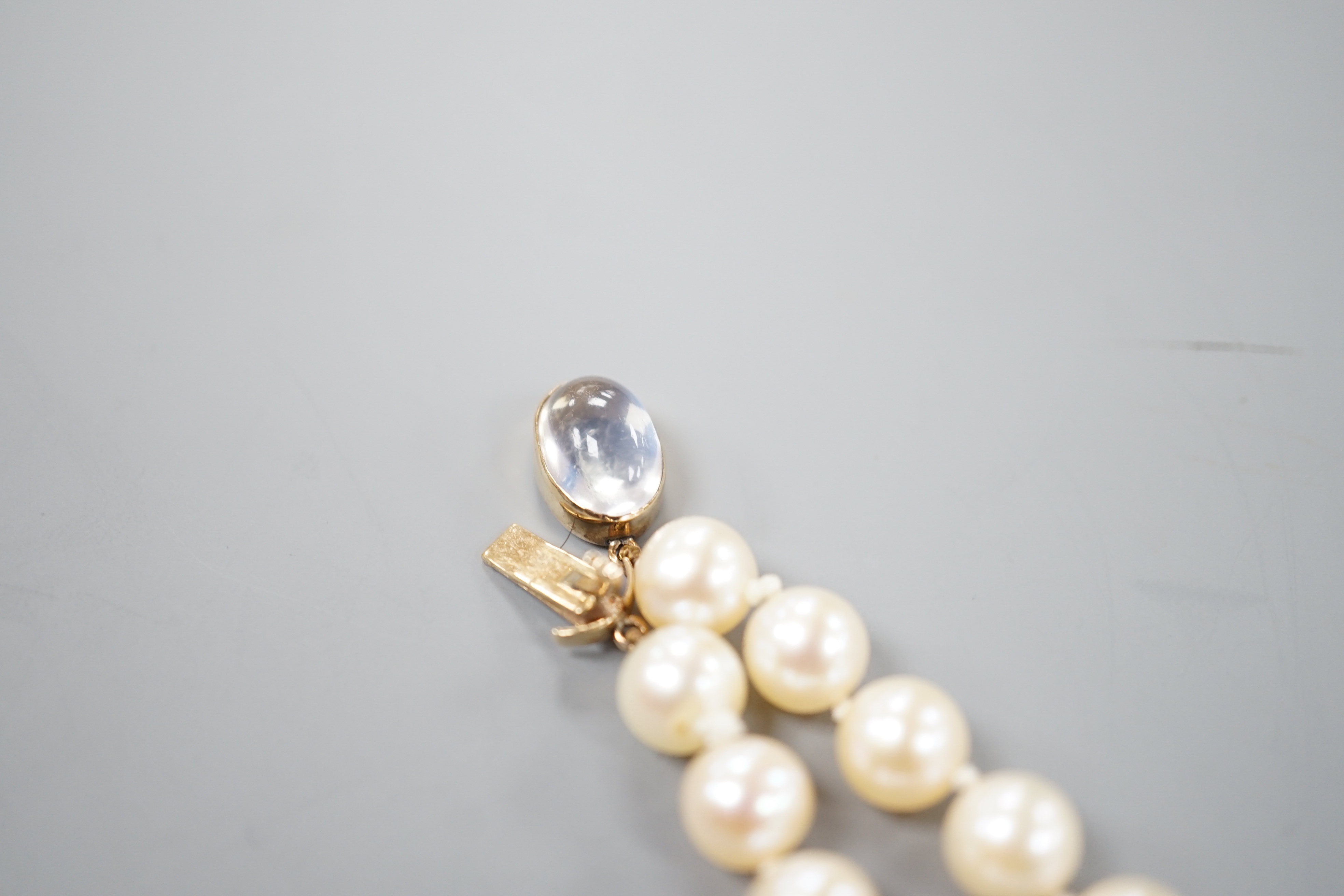 A single strand cultured pearl necklace, with yellow metal and moonstone set clasp, 56cm.